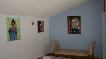 Una habitación con un sofá, una mesita con revistas y tres cuadros en la pared.