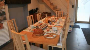 A dining area with a wooden table set for a meal, surrounded by chairs. A staircase is visible in the background.