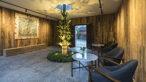 Ein modernes Interieur mit Holzwänden, einer zentralen Pflanze und Sitzbereichen.
