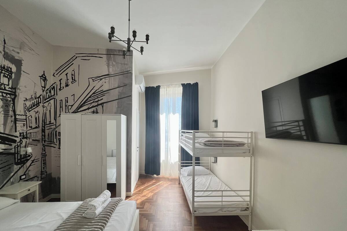 Een kamer met een stapelbed, een bureau, een kledingkast en een muurschildering.