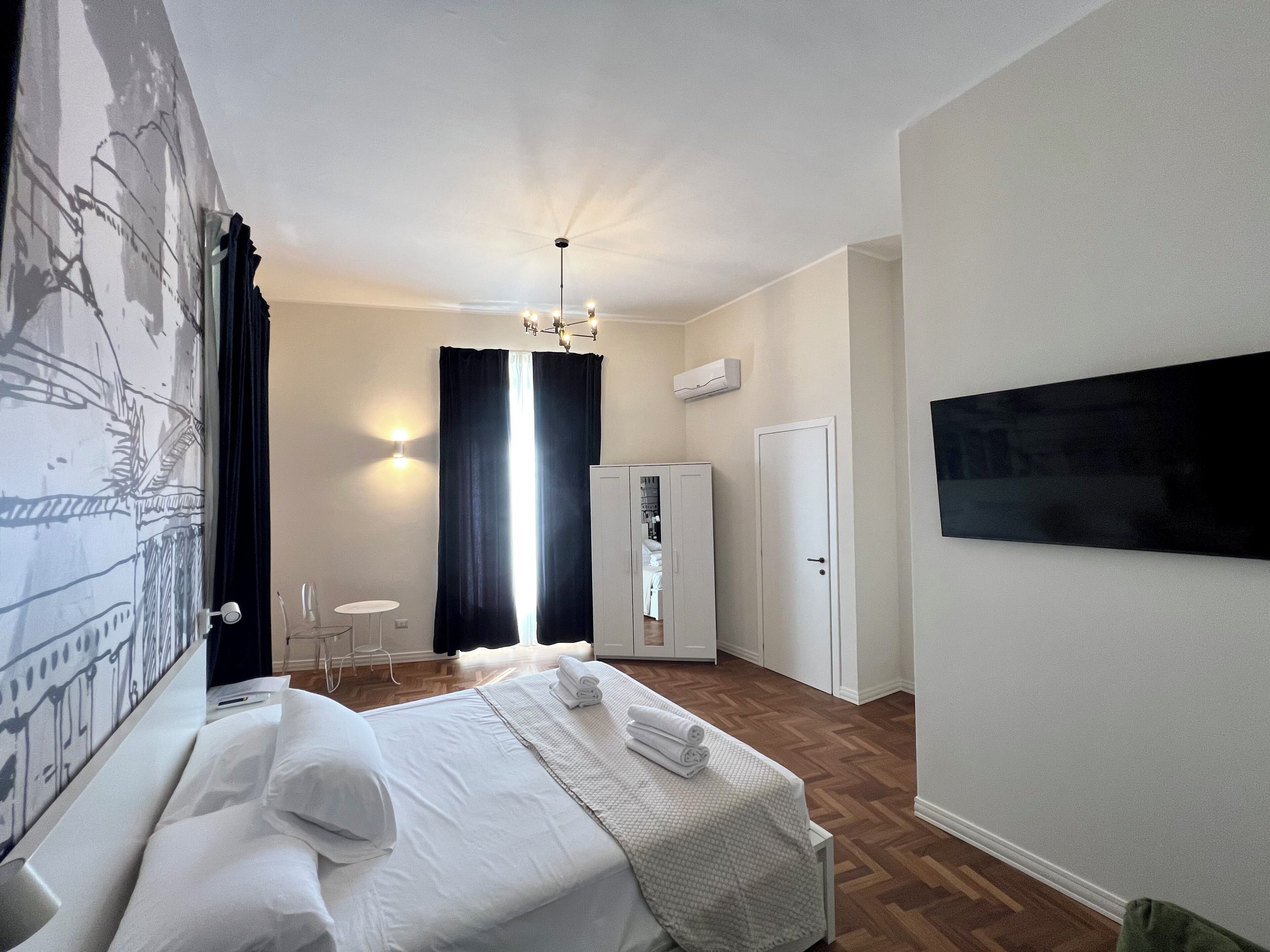 Una habitación de hotel con cama, escritorio, silla, armario y televisor.