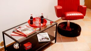 A modern living room with a red armchair, a glass coffee table with magazines, a tray with Coca-Cola bottles, and a magazine titled "Living". - Home2Rome - Trastevere Galletti (Rome)