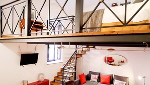A modern loft-style apartment with a staircase, a sofa set, and a dining area. - Home2Rome - Trastevere Galletti (Rome)