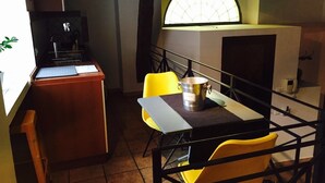 A small dining area with a table, chairs, a coffee machine, and a window with a view. - Home2Rome - Trastevere Mercanti I (Rome)