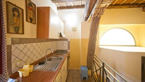 A narrow kitchen with a wooden ceiling, a sink, and a window. - Home2Rome - Trastevere Mercanti I (Rome)