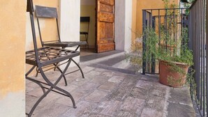 A patio with a metal table and chairs, a wooden door, a potted plant, and a metal fence. - Home2Rome - Trastevere Mercanti I (Rome)