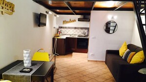 A compact living space with a dining area, kitchenette, and a sofa with yellow cushions.