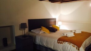 A neatly made bed with a white and brown blanket, a headboard, and a bedside lamp.
