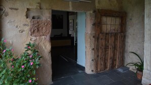 Una entrada rústica con puerta de madera y pared de piedra.