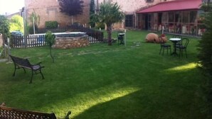 Un patio con una fuente de piedra, un banco y mesas al aire libre.