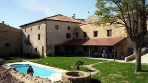 Un edificio de piedra con piscina y un pequeño jardín.