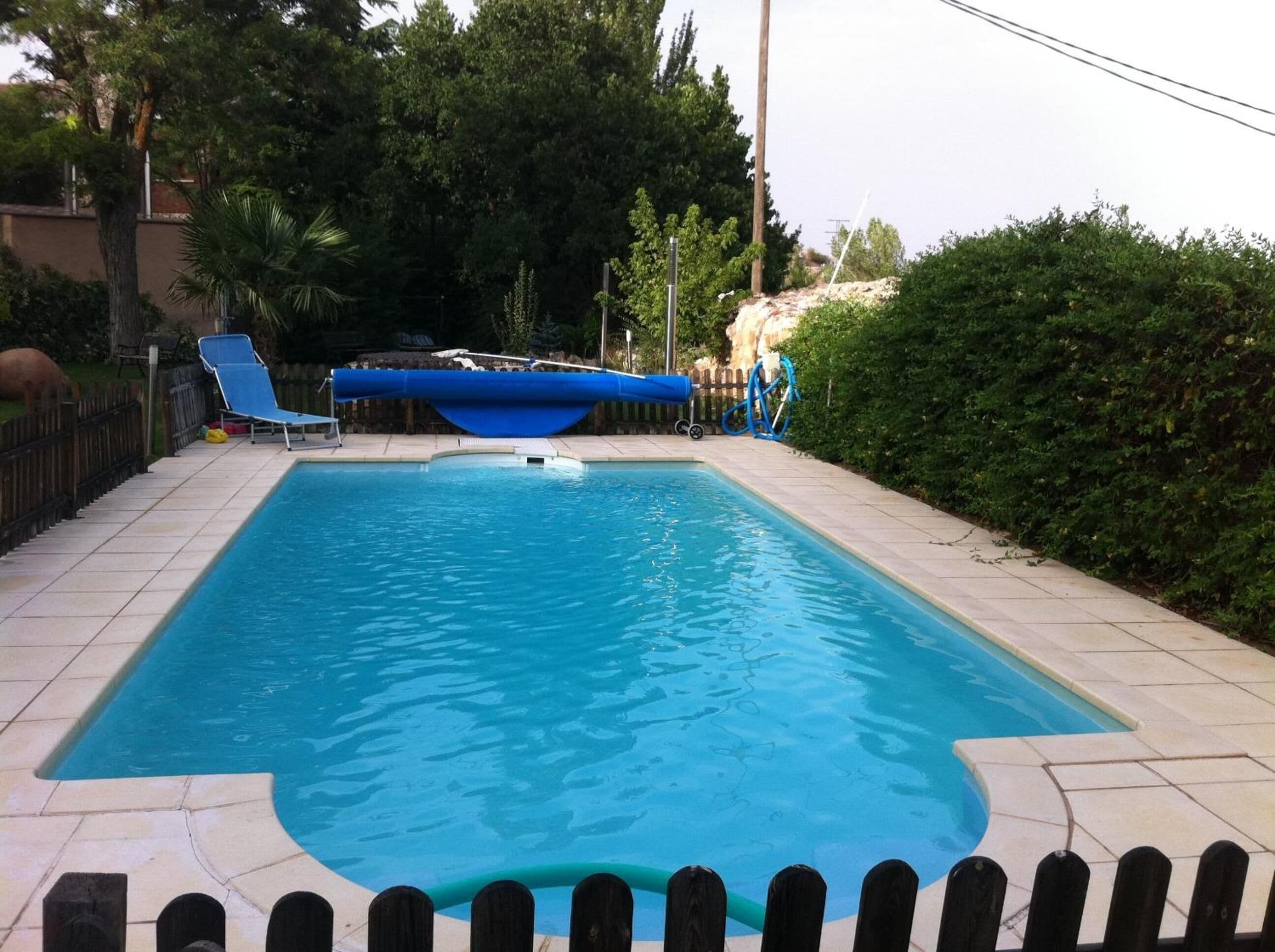 Een buitenzwembad, ligstoelen bij het zwembad