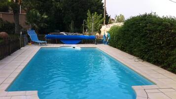 Een buitenzwembad, ligstoelen bij het zwembad