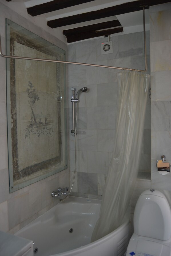 Un baño con bañera, ducha e inodoro.