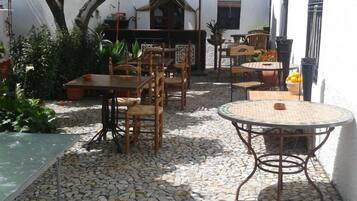 Un patio al aire libre con piso de piedra, mobiliario de madera y una piscina pequeña.