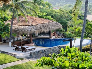 A pool area with lounge chairs and a thatched-roof structure. - Casa Manzanillo Boutique Hotel (Troncones)