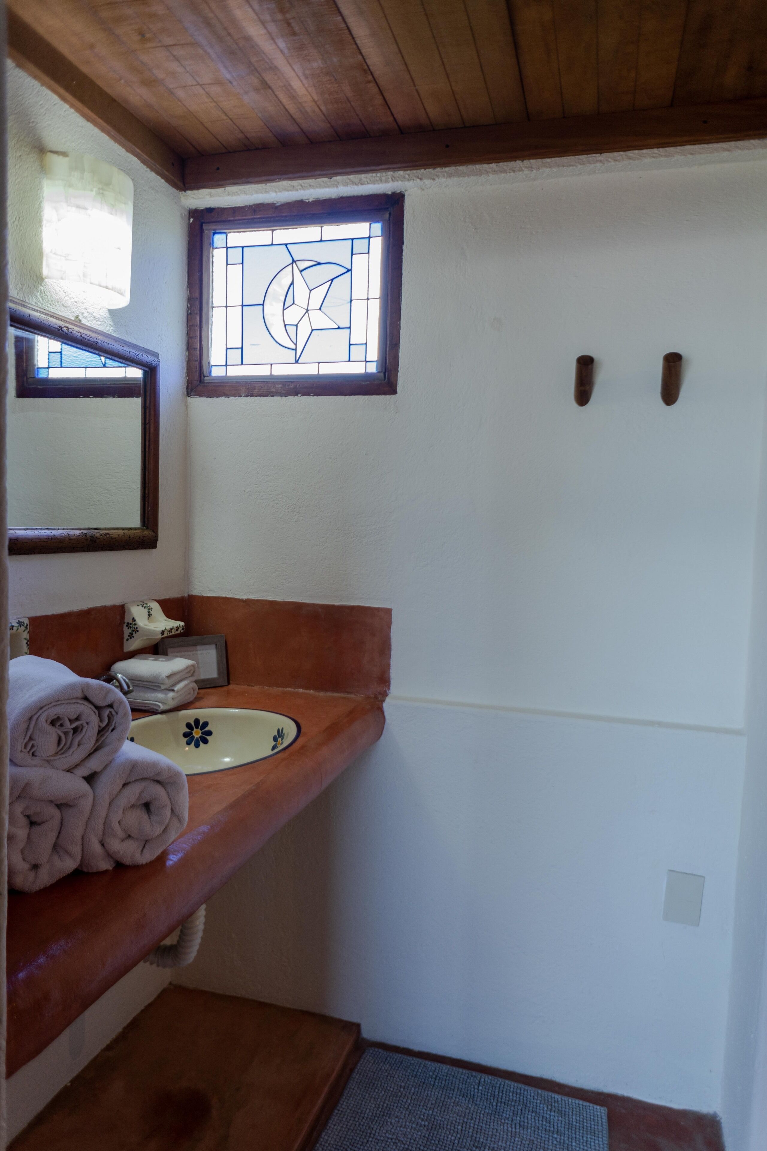 Casa de banho com toucador de madeira, lavatório branco e espelho.