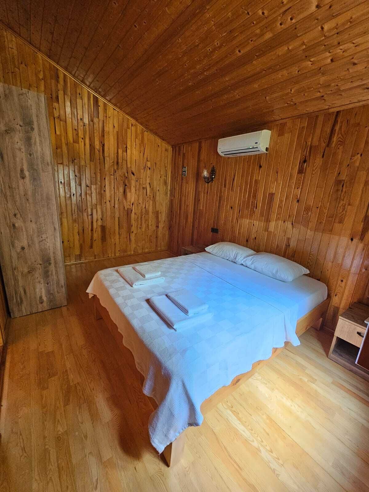 Una habitación con paneles de madera, una cama, una mesita de noche y un equipo de aire acondicionado.