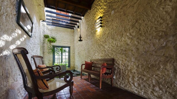 Um interior rústico com parede de pedra, móveis de madeira e luminária pendente.