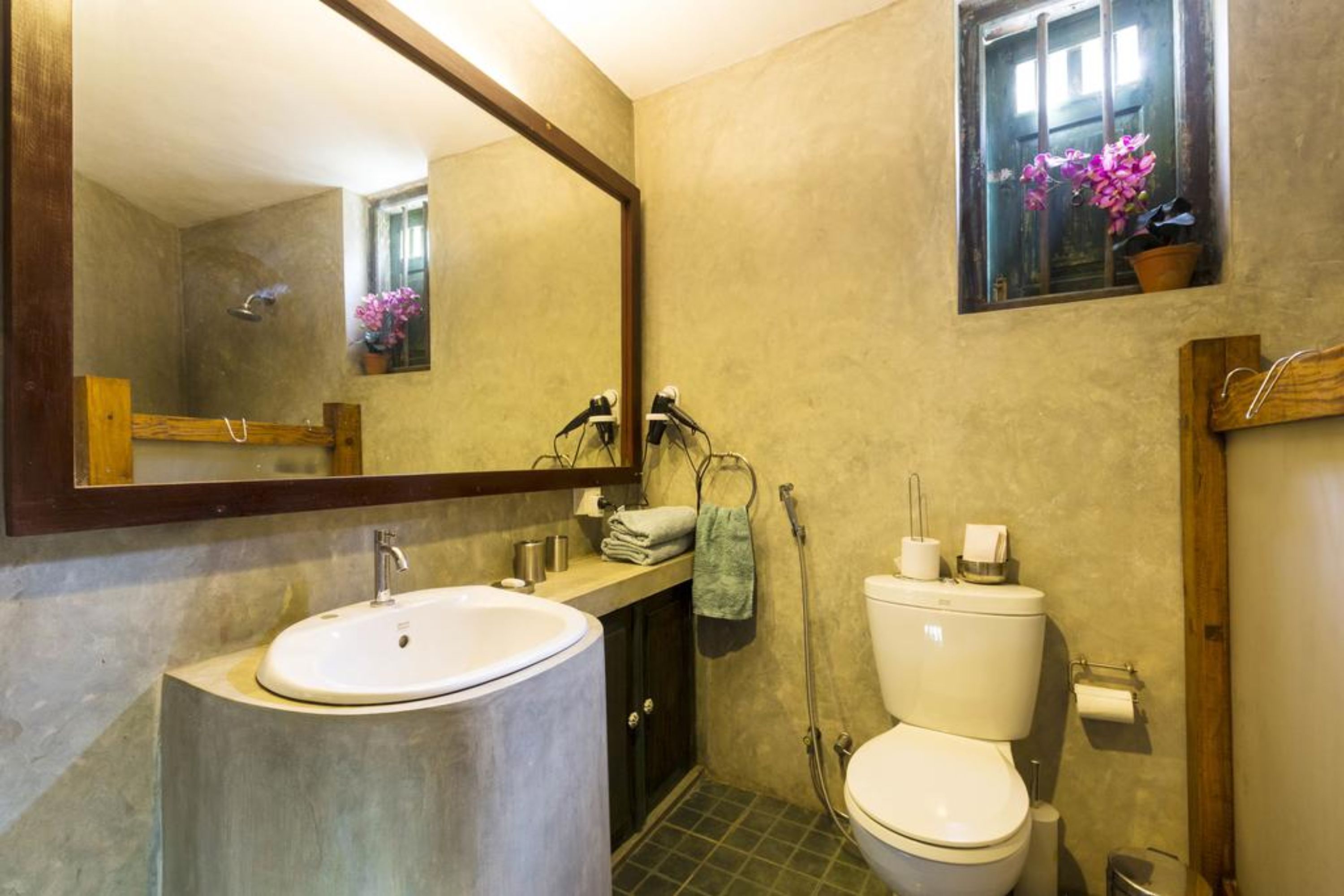 A bathroom with a large mirror, a sink, a toilet, and a shower.