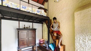 Um quarto com uma cama de solteiro e beliche, um armário de madeira e uma pessoa lendo um livro.