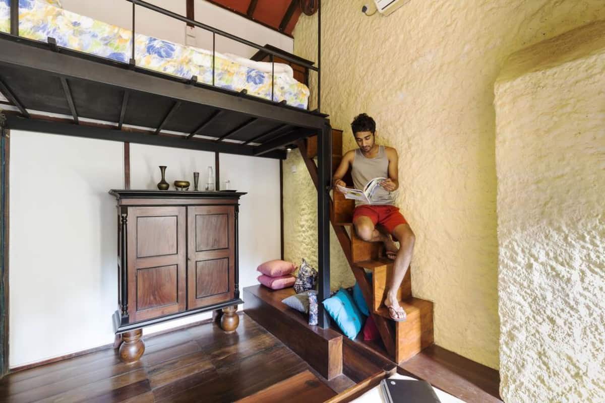 A room with a bunk bed, a wooden cabinet, and a person reading a book.