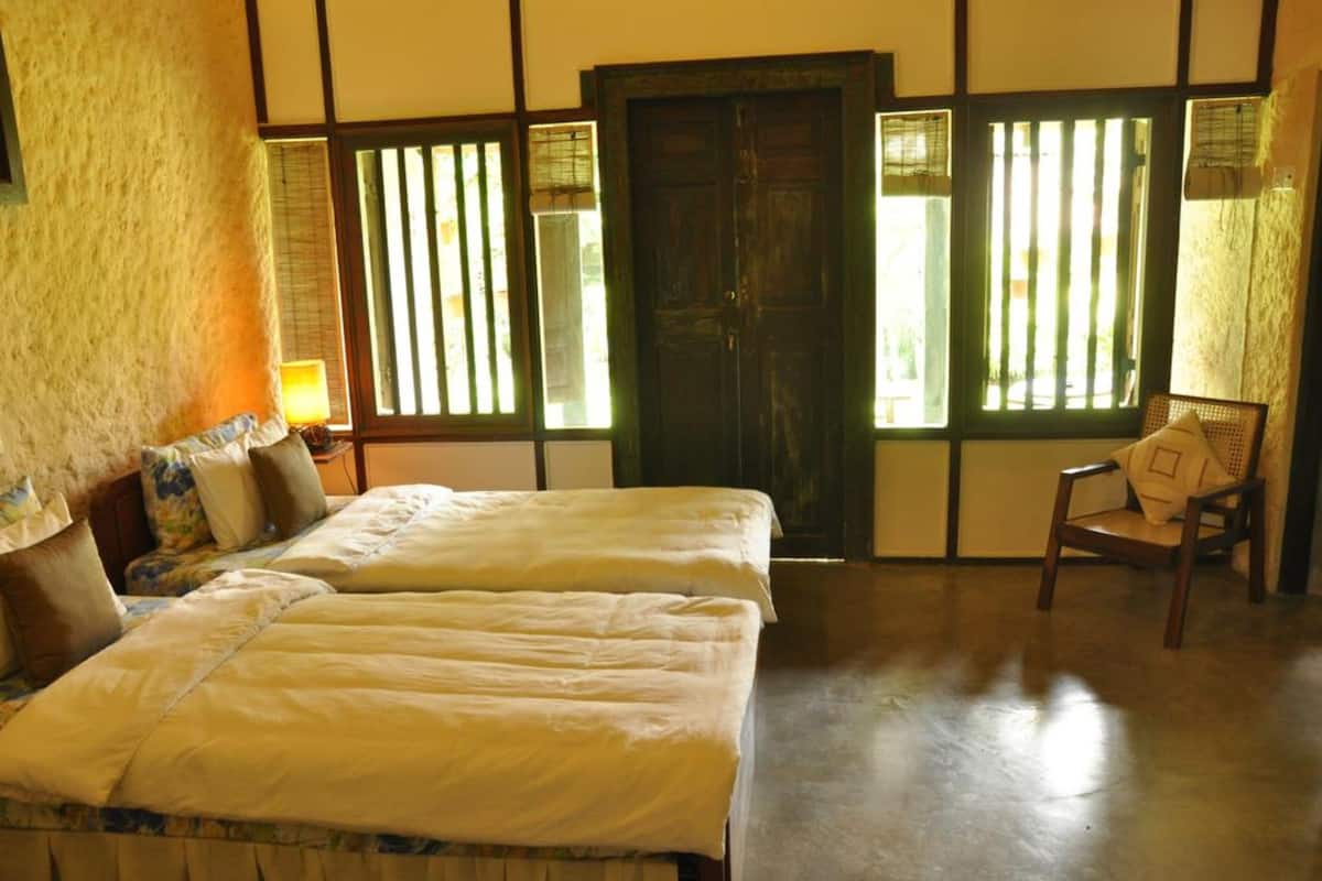 A room with two beds, a chair, and a door.