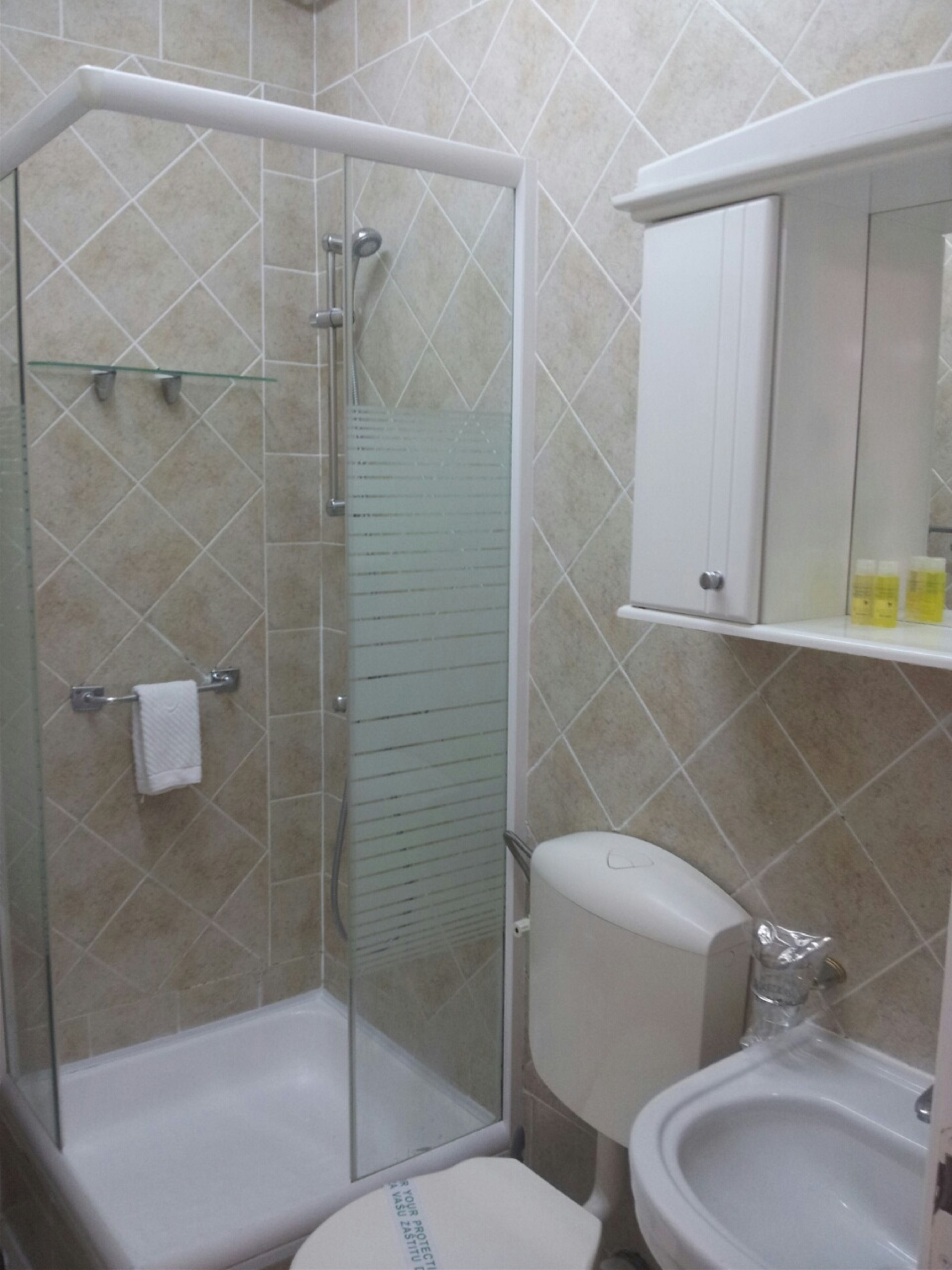 A bathroom with a glass-enclosed shower, a toilet, and a sink.