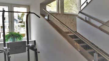 A staircase with handrails, a window with a view of buildings, and a potted plant.