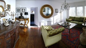 Un salon avec un canapé vert, un meuble en bois et un grand miroir.