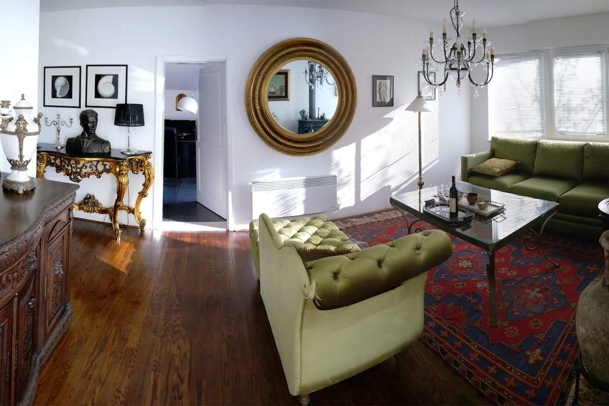 Una sala de estar con un sofá verde, un aparador de madera y un espejo grande.