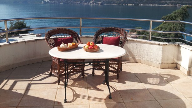 Une terrasse avec des fauteuils en osier et une table décorée de fruits et de bougies.