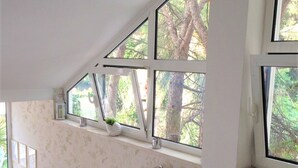 Un escalier avec une rampe, une fenêtre donnant sur des arbres et un mur orné d’un motif floral.