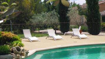 A swimming pool with lounge chairs and a garden area.