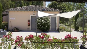 Un bâtiment doté d’un toit en tuiles, d’un patio couvert et d’un jardin agrémenté de fleurs roses.