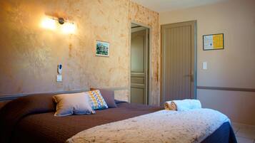 A hotel room with a large bed, a nightstand, a wall-mounted light, and a door leading to another room.