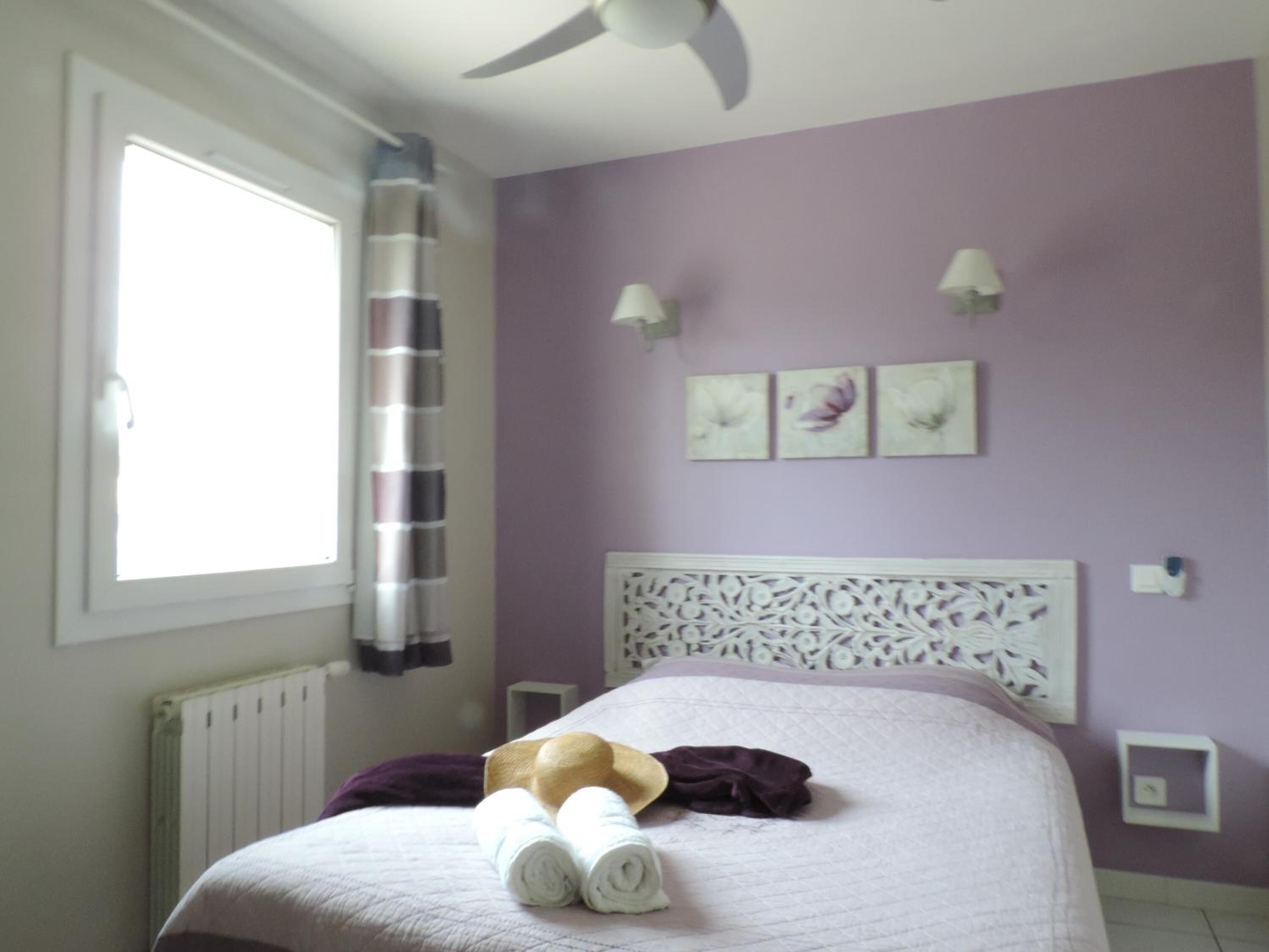 A bedroom with a bed, a window, a radiator, and a ceiling fan.