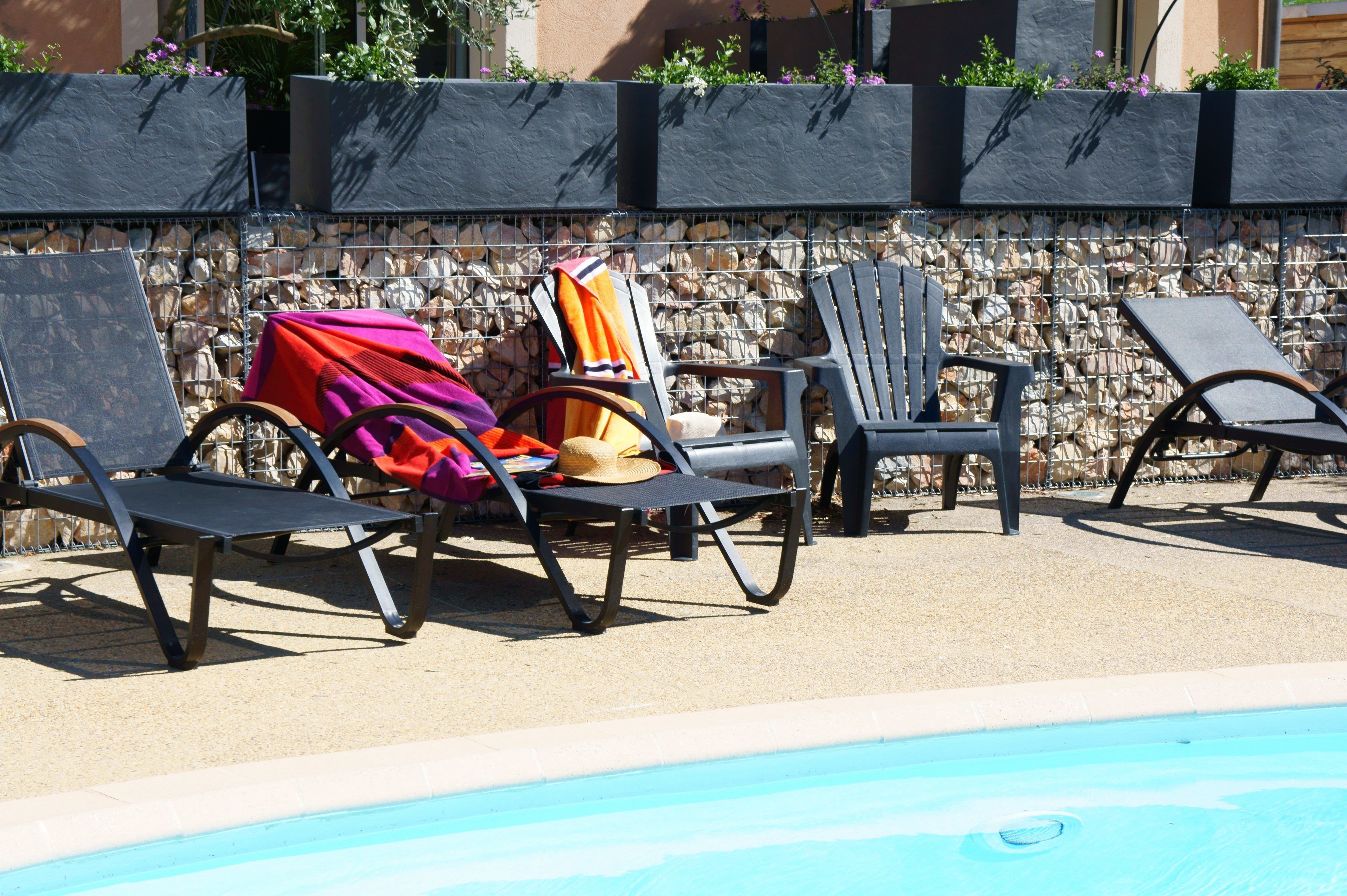A poolside area with lounge chairs and a stone wall.