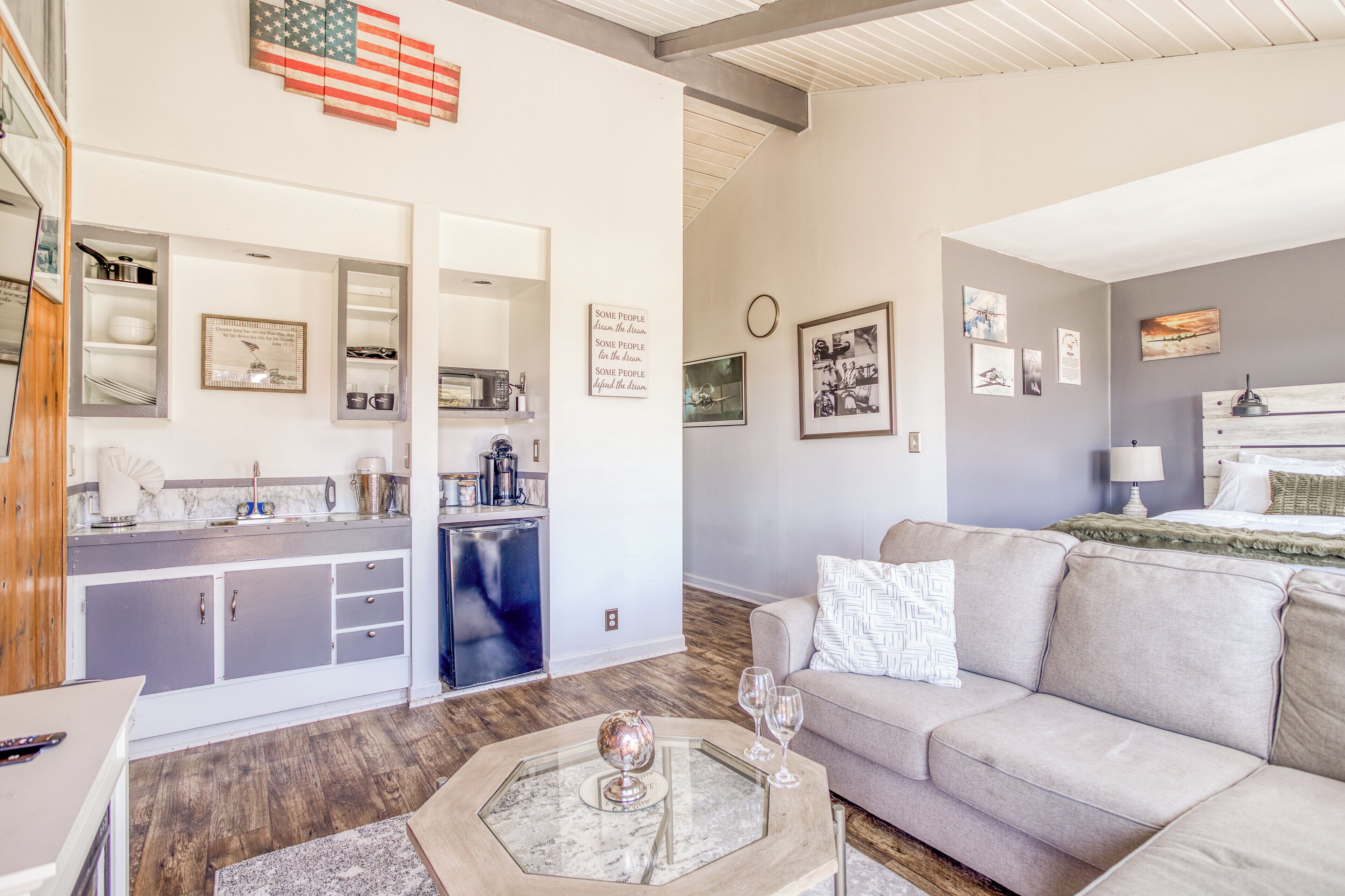 Een moderne woonkamer met een bank, salontafel en een keukenhoek met kasten en een koelkast.