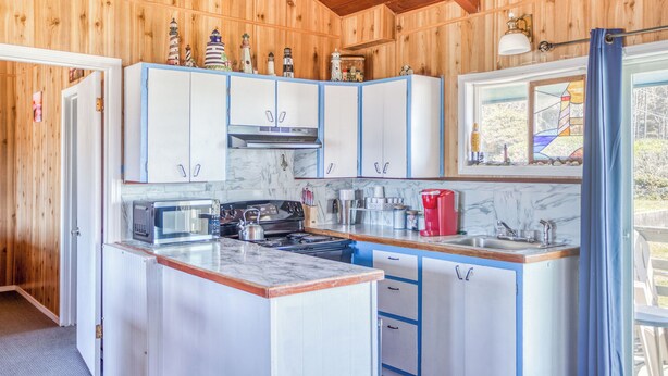 Une cuisine compacte aux murs en bois, dotée d’un plan de travail en marbre et d’un petit îlot central.