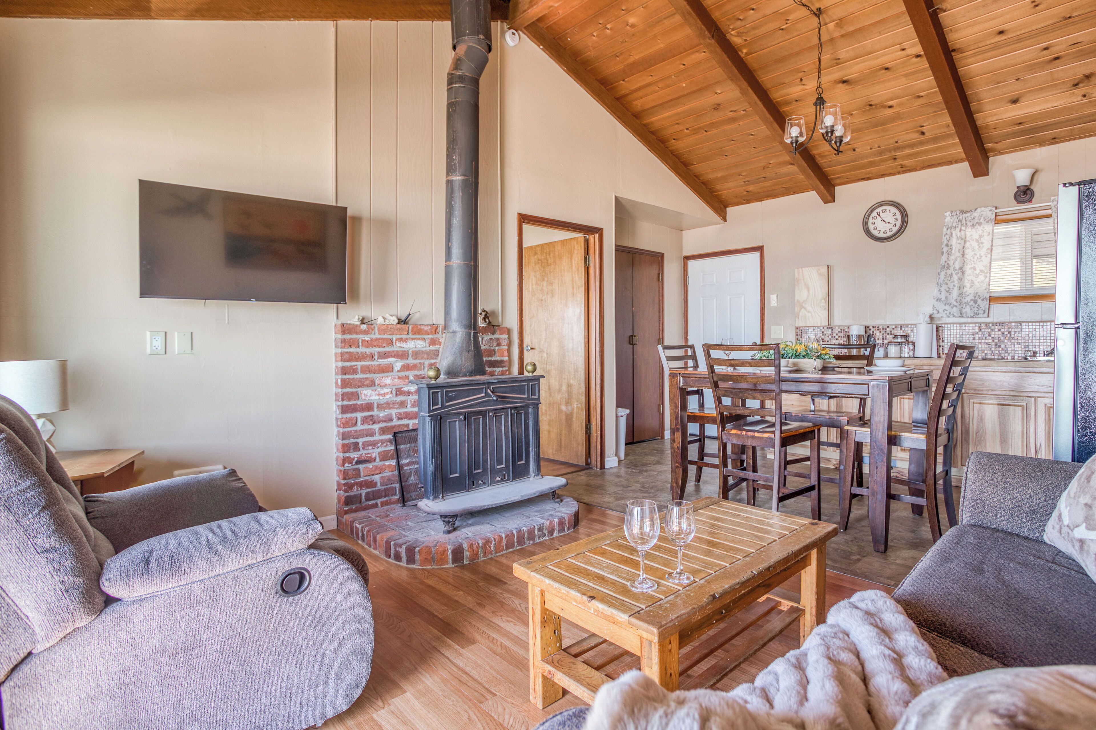 A cozy living room with a fireplace, wooden furniture, and a TV mounted on the wall.