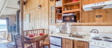 A wooden kitchen with a refrigerator, stove, microwave, and wooden shelves.