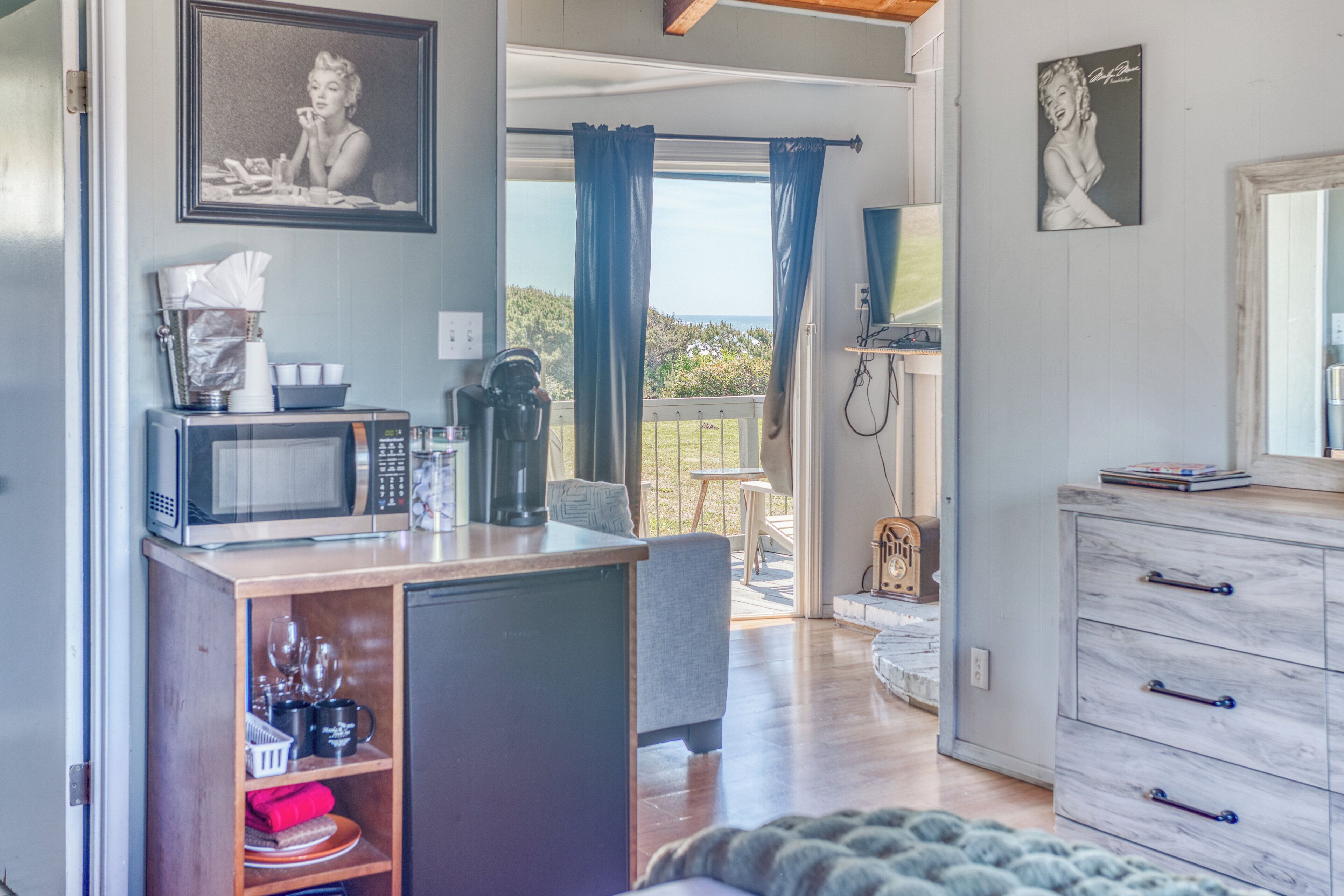 A compact room with a kitchenette, a dining area, and a view of the outdoors.