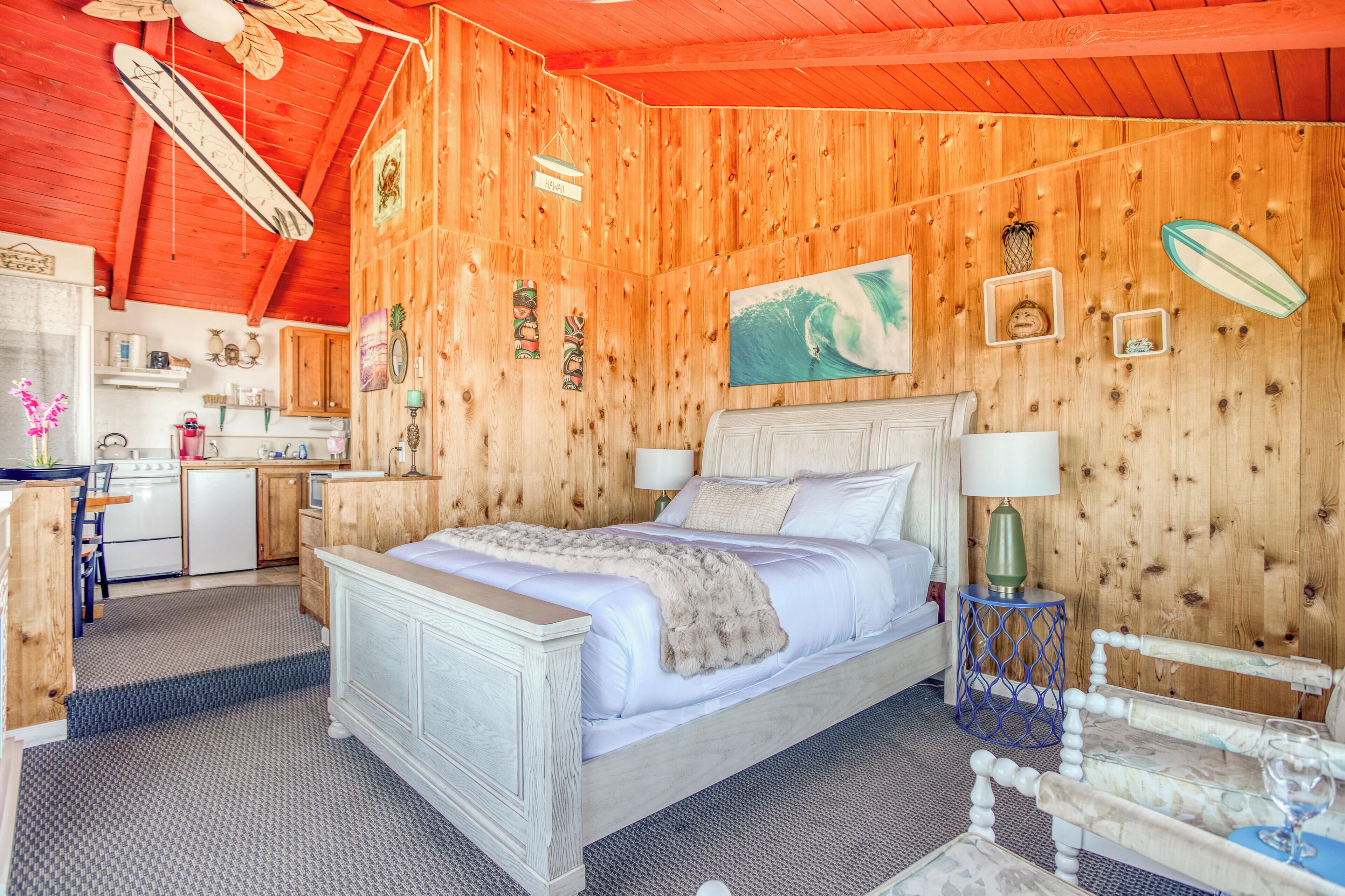 A wooden-themed bedroom with a bed, bedside tables, and a small desk area.