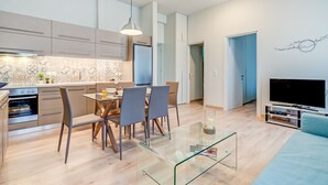 A modern kitchen with a dining area, a glass coffee table, and a flat-screen TV in a living room. - Casa 1926 (Chania)