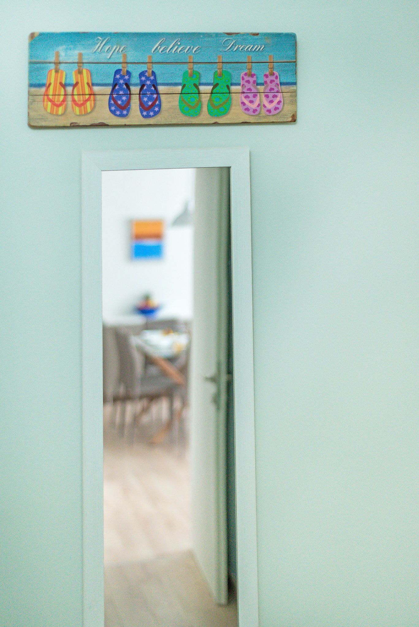 Un marco de puerta con un letrero de madera que muestra chanclas y las palabras 'Hope', 'believe' y 'Dream'.