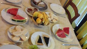 A dining table set with various plates of food, including watermelon slices, bread, and a dessert. - Agriturismo Cascina Rossano (Provaglio d'Iseo)