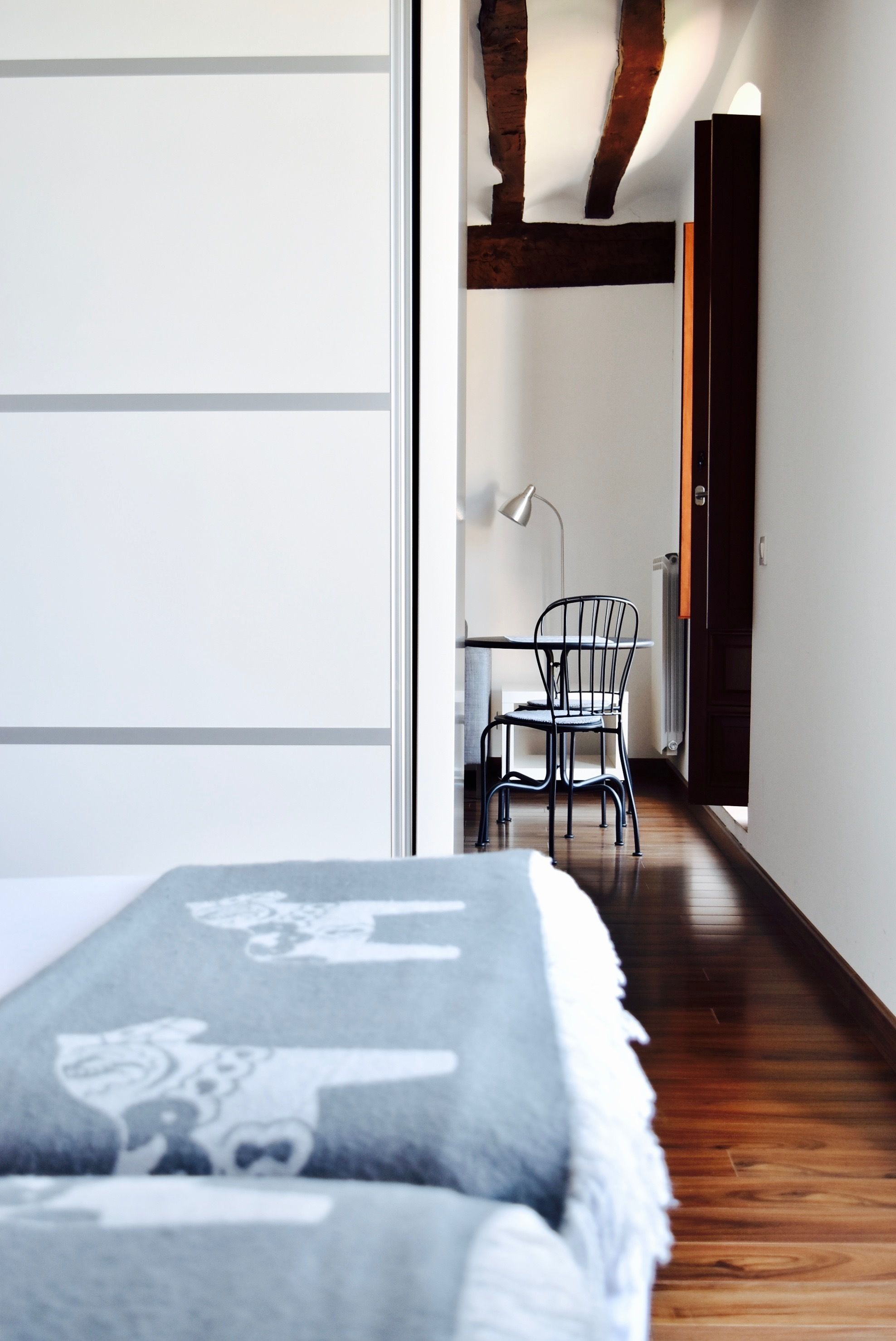 Un dormitorio con una cama, una silla y un escritorio con lámpara.