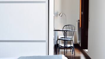 Un dormitorio con una cama, una silla y un escritorio con lámpara.