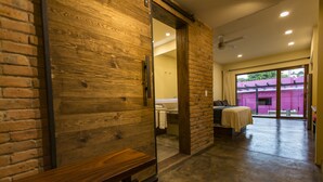 A modern bathroom with a wooden bench, a shower area, and a view of a pink building outside. - Casa de la Ballena (Sayulita)